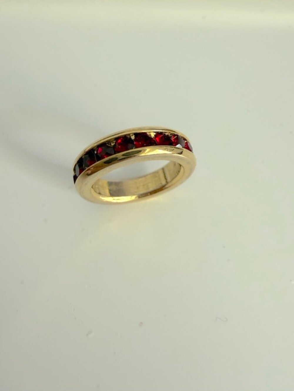 An eternity band charm ring featuring channel-set, round red gemstones